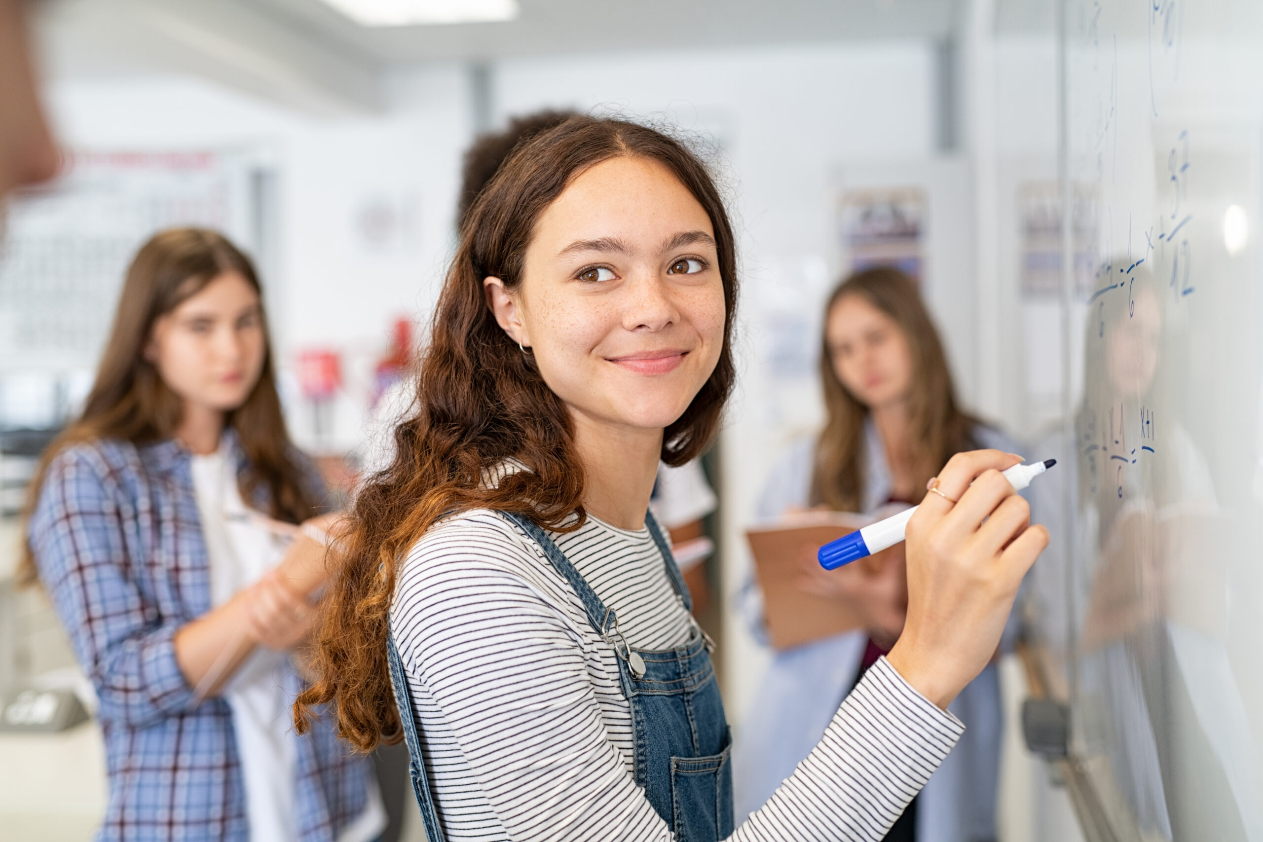 Ung student som löser en matteekvation på tavlan i klassrummet under lektionstid.